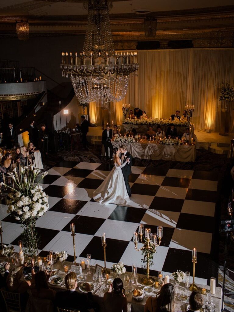Bride and groom dancing on a checkered floor in a luxury ballroom