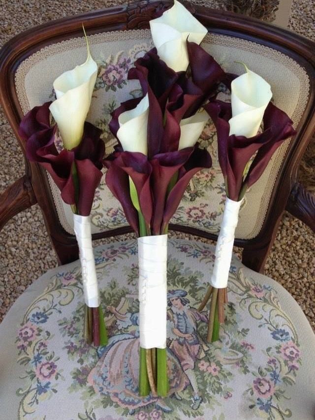 Burgundy and white calla lily bouquets resting on a vintage floral chair