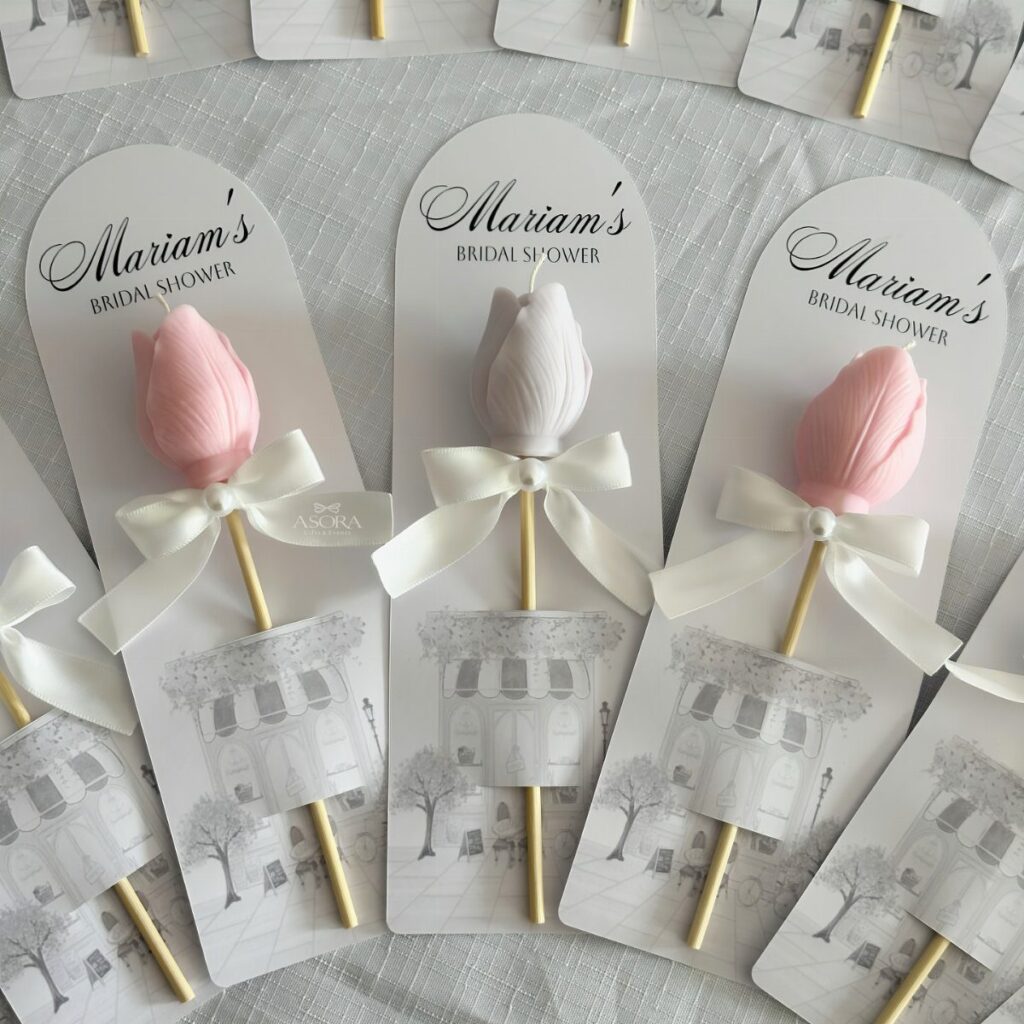Tulip-shaped pink and white candles on sticks with bridal shower cards.