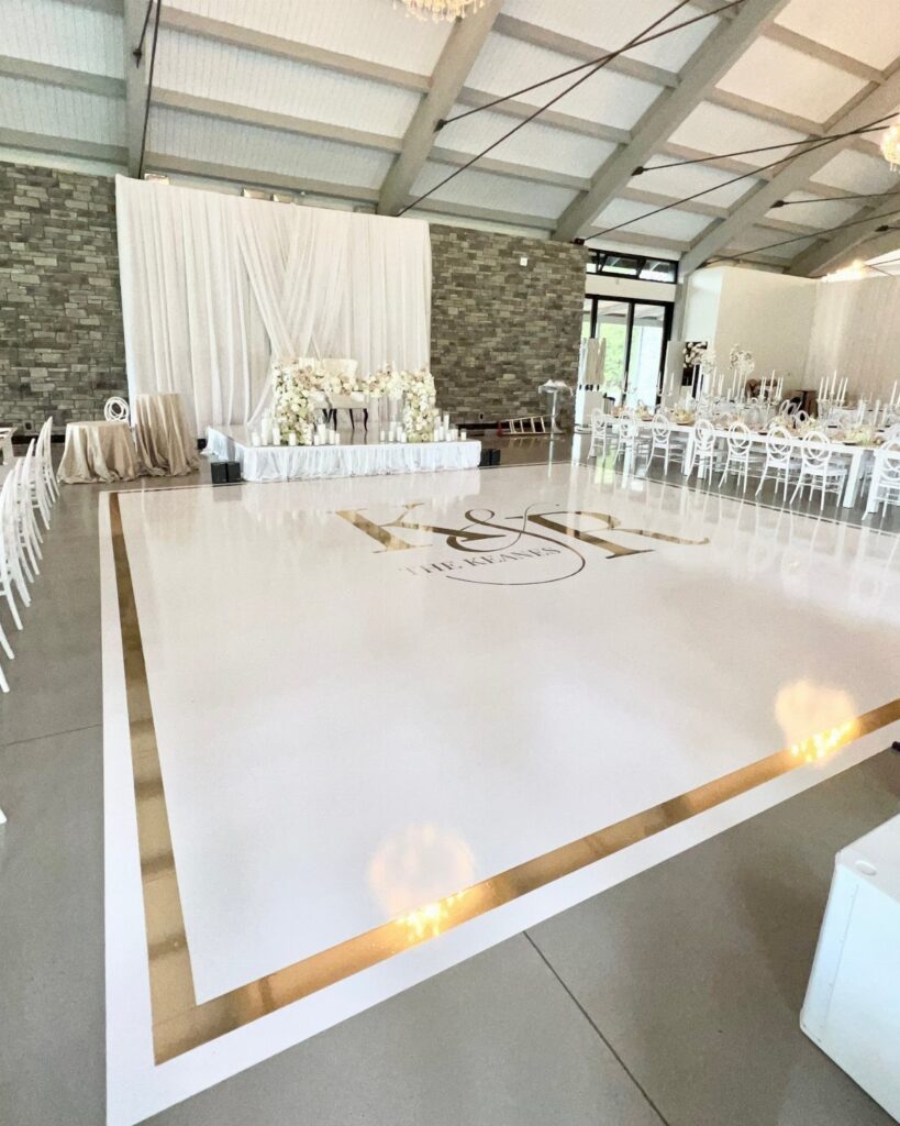 White glossy wedding dance floor with gold borders and a central gold monogram.
