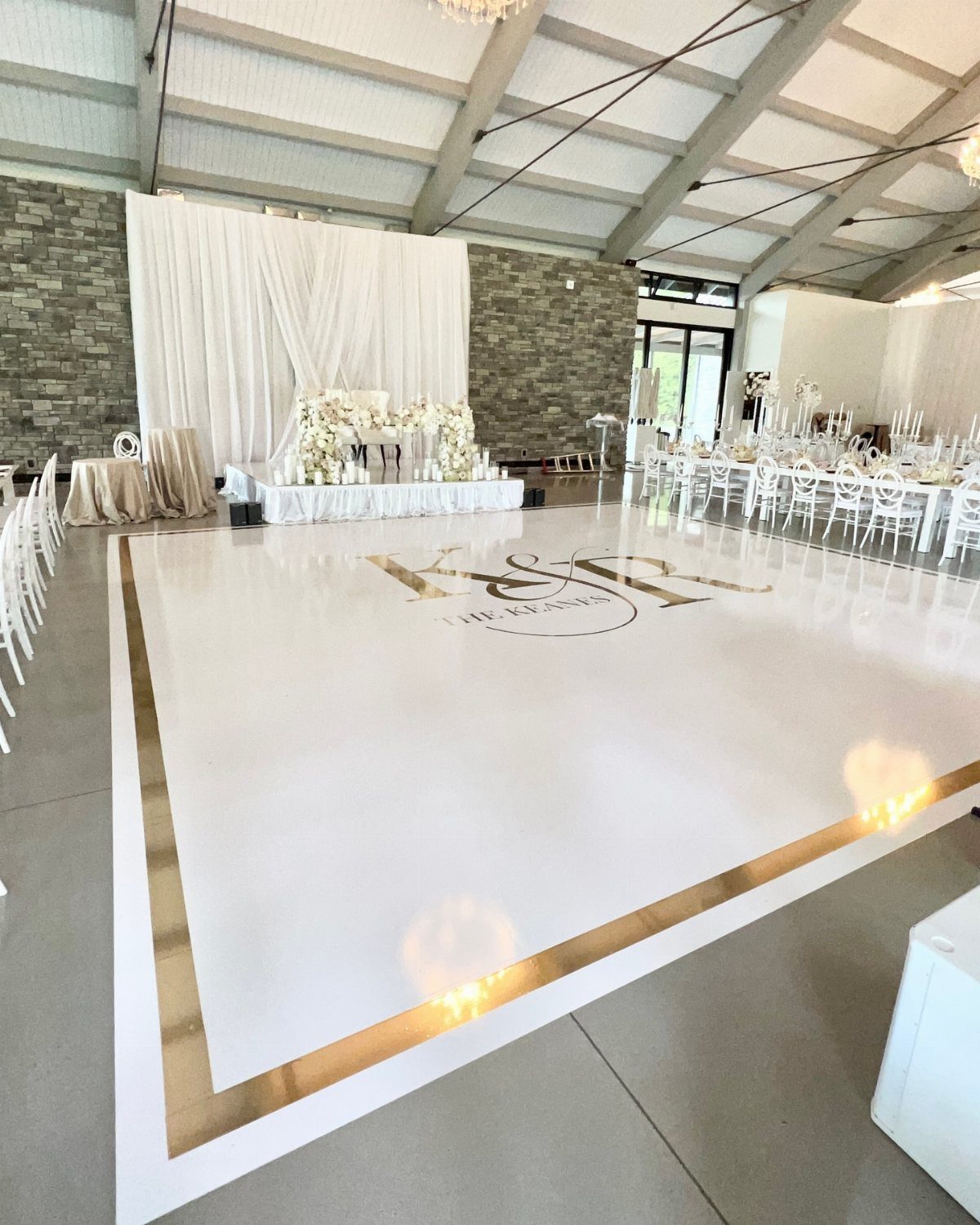 White glossy wedding dance floor with gold borders and a central gold monogram.