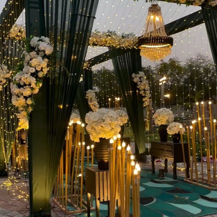 Emerald green wedding decor with white flowers, a chandelier, and warm glowing lights.
