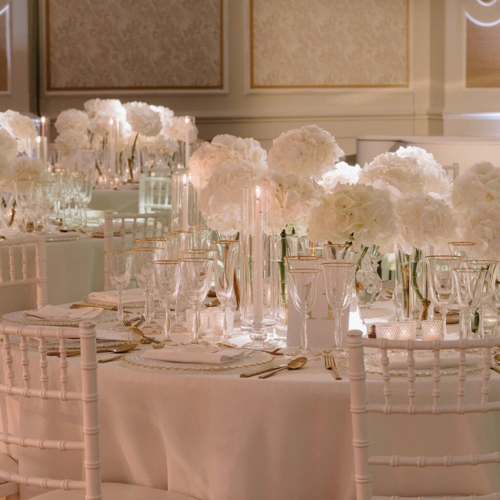 White hydrangea floral centerpieces and candles on a formal wedding reception table.