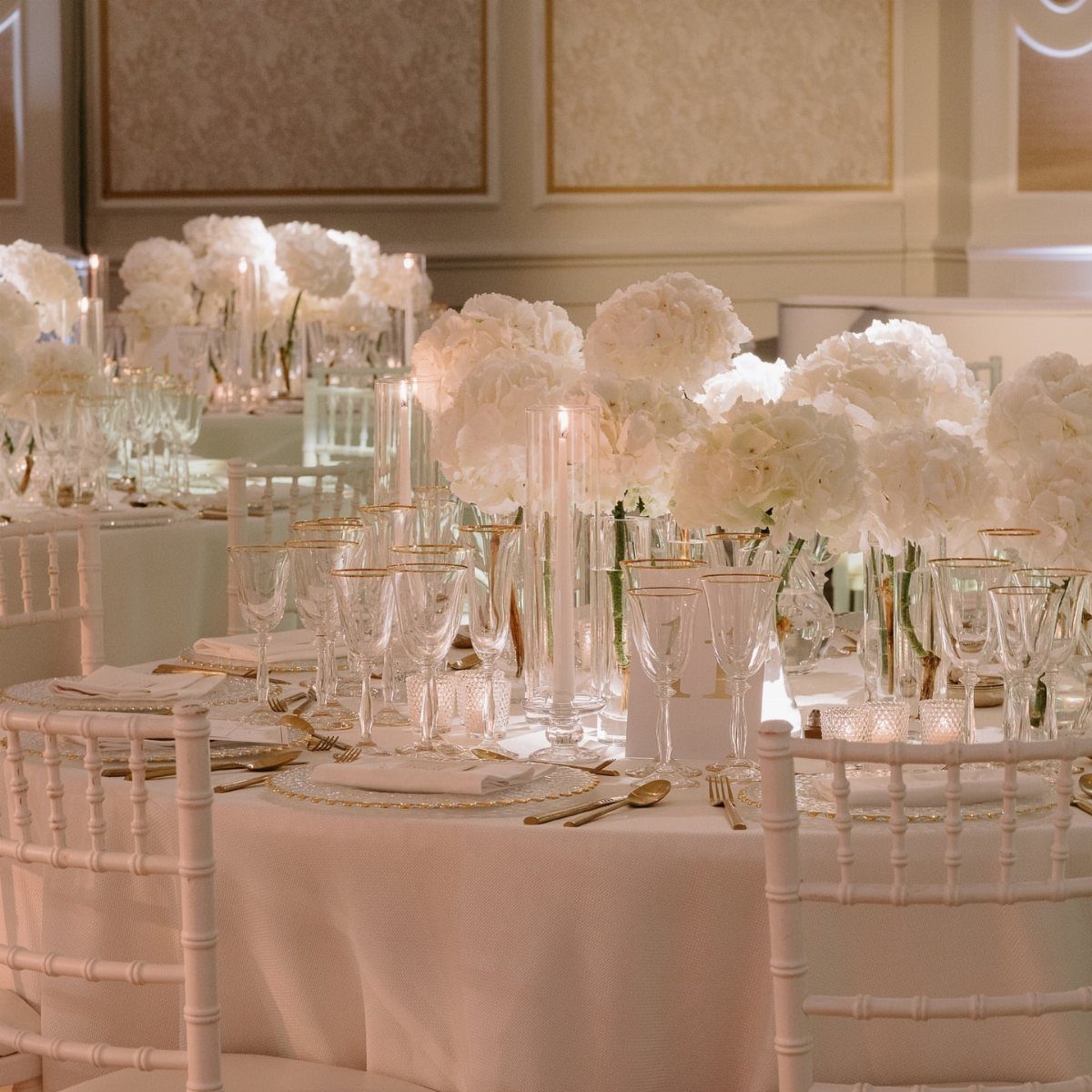 White hydrangea floral centerpieces and candles on a formal wedding reception table.