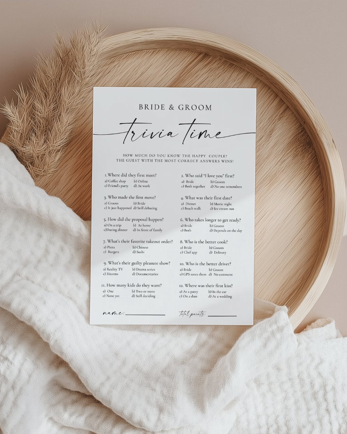 Trivia card for a bride and groom on a wooden tray with white fabric.