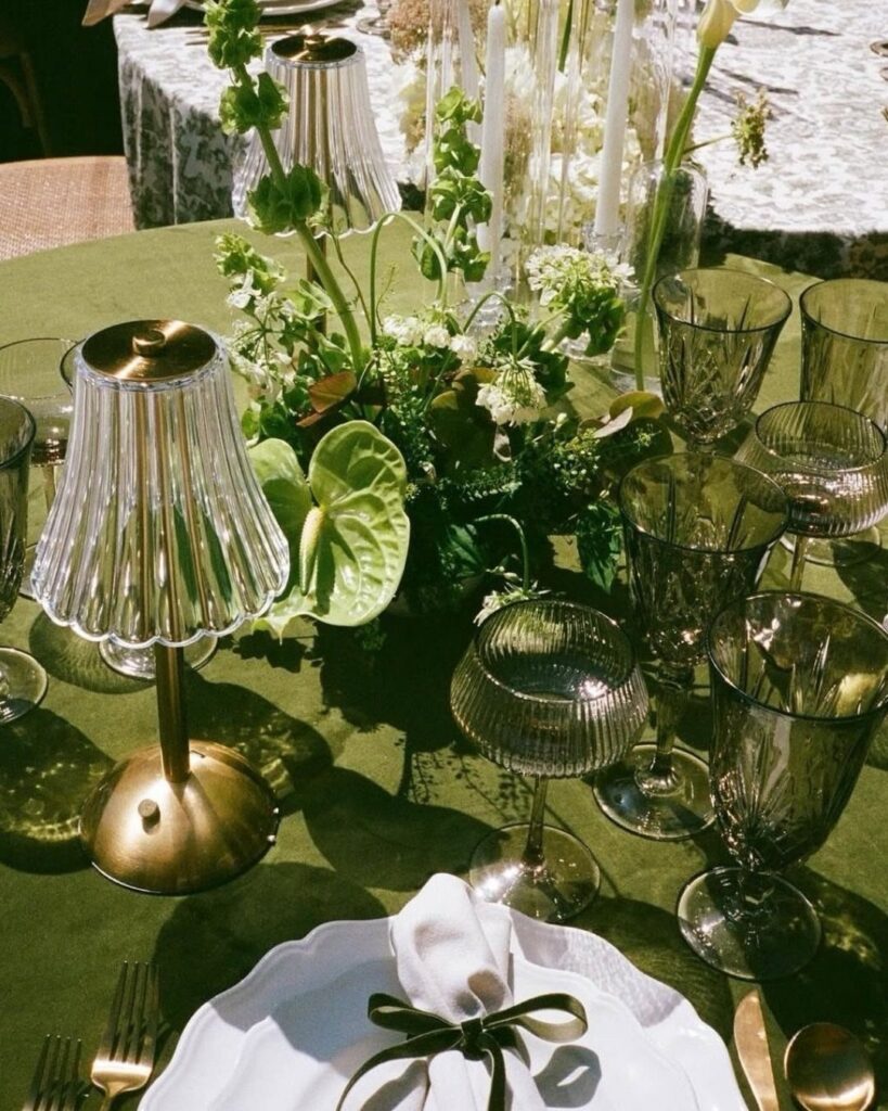 Green wedding table setting with green linens, tinted glasses, and white floral centerpieces.