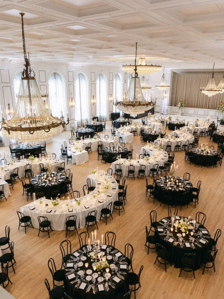 Grand ballroom with round and curved tables set for a wedding reception dinner.