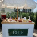 Outdoor snack bar with appetizers and drinks under a white fringed umbrella
