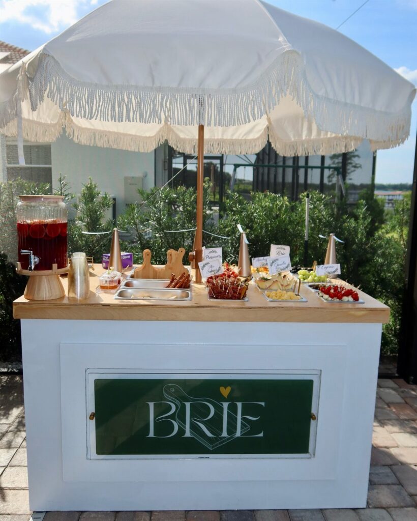 Outdoor snack bar with appetizers and drinks under a white fringed umbrella